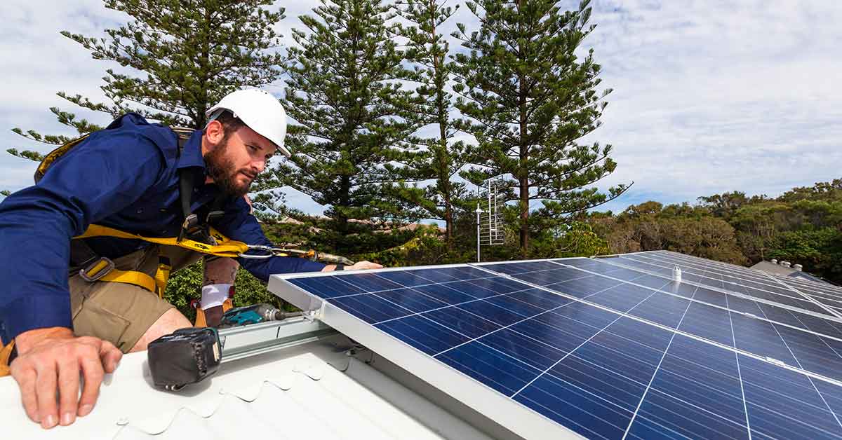 Handwerker montiert Photovoltaikanlage auf Hausdach | Energieautarkes Haus